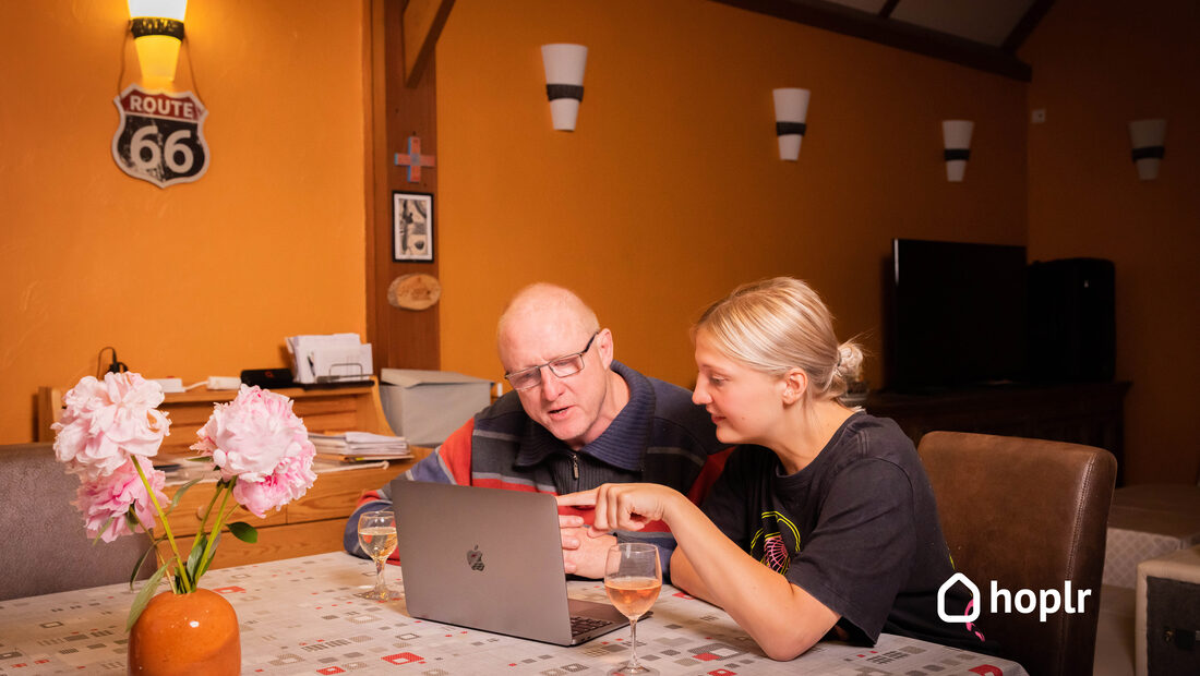 Two neighbours sort something out together on a laptop